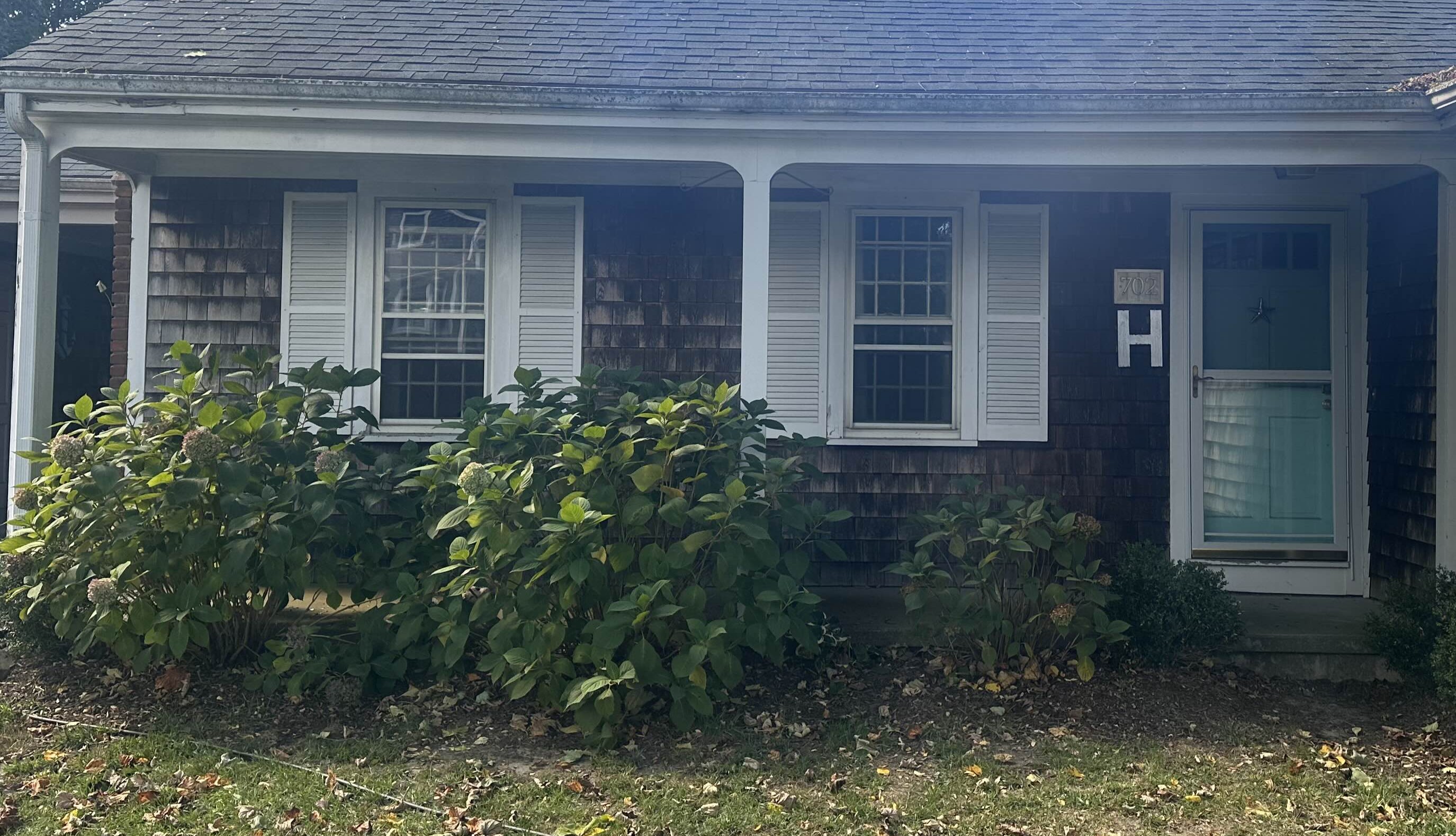 Cedar shake siding front of house before cleaning Middletown RI - severely weathered dark gray appearance